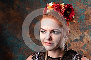 Woman in red circlet of flowers looking away in front of teal and orange background