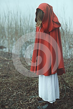 Woman with red cloak in misty desolated land