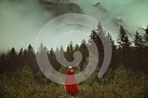 Woman with red cloak in a misty forest