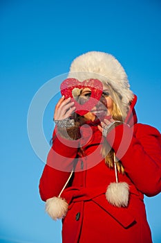 Woman in red coat looking through heart shape