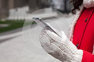 Woman in red coat with smartphone in hands going through the cit