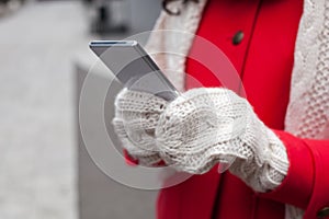 Woman in red coat with smartphone in hands going through the cit