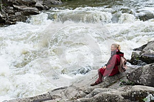 Woman in red coat standing on the banks of deep Prut river in Yaremche, Ukraine
