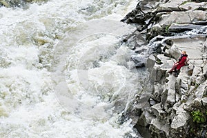 Woman in red coat standing on the banks of deep Prut river in Yaremche, Ukraine