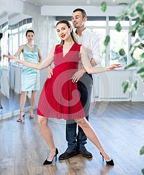 Woman in red dancing passionate bachata with man at dance class