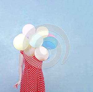 Woman in red dotty dress holding pastel balloons