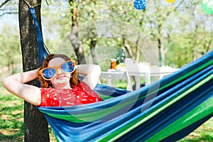 Woman in red dress and big funny sun glasses lying on hammock