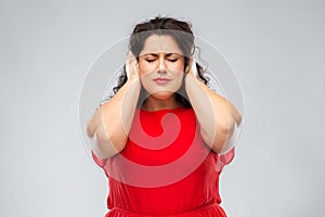 Woman in red dress closing her ears by hands