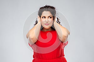 Woman in red dress closing her ears by hands