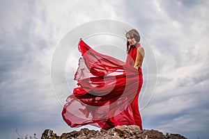 Woman in red dress dance over storm sky, gown fluttering fabric flying as splash