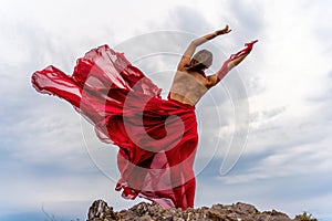 Woman in red dress dance over storm sky, gown fluttering fabric flying as splash