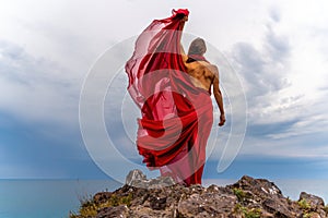 Woman in red dress dance over storm sky, gown fluttering fabric flying as splash