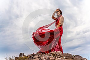 Woman in red dress dance over storm sky, gown fluttering fabric flying as splash