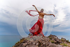 Woman in red dress dance over storm sky, gown fluttering fabric flying as splash