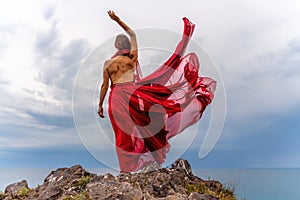 Woman in red dress dance over storm sky, gown fluttering fabric flying as splash