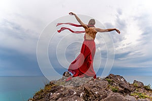 Woman in red dress dance over storm sky, gown fluttering fabric flying as splash