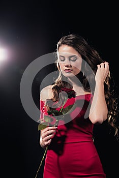 woman in red dress with eyes closed holding rose