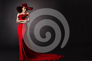 Woman red Dress and Hat. Fashion Model in Long evening Gown with Flowers. Black Studio Background