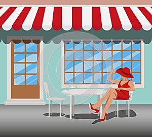 woman in a red dress and hat sits on a chair in a summer cafe