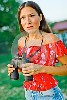 Woman in red dress holding binoculars