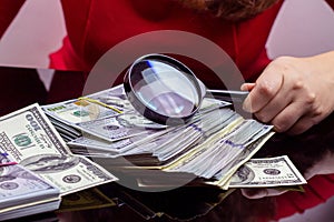 Woman in red dress holding and counting cash money american dollars in her hands on black table background