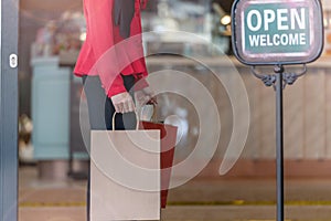 Woman in red dress holding shopping bag and walking to shop building. Concept people activity in shopping festival season