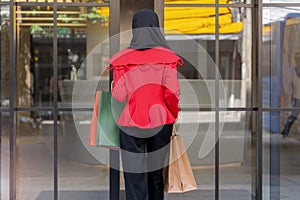 Woman in red dress holding shopping bag and walking to shop building. Concept people activity in shopping festival season