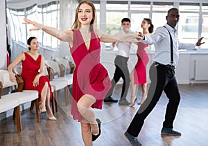 Woman in red dress practicing playful jitterbug in dance studio