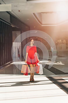 woman in red dress with shopping bags walking around the mall