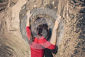 Woman in red dress touching rock wall