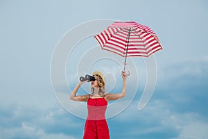 Woman in red dress with umbrella and binoculars