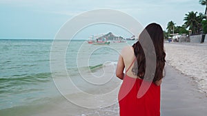 Woman in red dress walking on sea beach