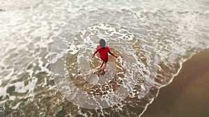 Woman in red dress walking into the water by sand beach on the seaside on sunset, inspirational freedom happy holidays