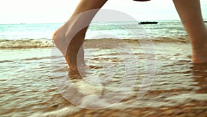 The woman in a red dress walks on the beach. Closeup of beautiful girl in summer dress