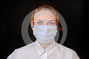 A woman with red eyes in a white shirt and a medical mask on a black background. People caught in isolation due to the flu virus