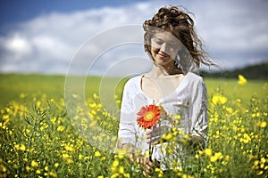 Woman with red flowers in rapeseed field.