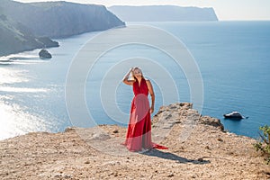 A woman in a red flying dress fluttering in the wind, against the backdrop of the sea.