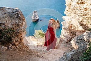 A woman in a red flying dress fluttering in the wind, against the backdrop of the sea.