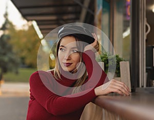 Woman in red golf posing among shops with coffee