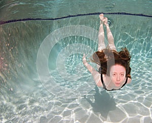 A woman with red hair in below or above the surface.