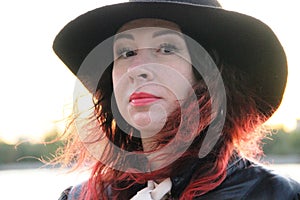 Woman with red hair and a classic black hat with a wide brim. after self-isolation.