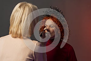 Woman with red hair doing makeup Beautician, applying powder to her face with a large brush, powdering the skin, selective focus.