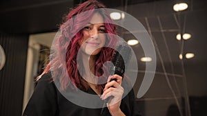 a woman with red hair is holding a hair dryer and smiling