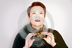 Woman with red hair looking through binoculars