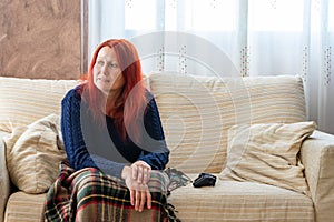 Woman with red hair playing game console on white sofa