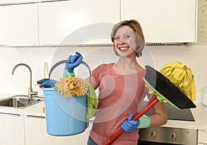 Woman with red hair in rubber washing gloves holding cleaning bucket mop and broom