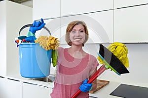 Woman with red hair in rubber washing gloves holding cleaning bucket mop and broom