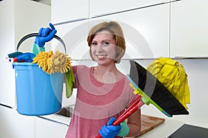 Woman with red hair in rubber washing gloves holding cleaning bucket mop and broom