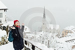 Woman in red hat enjoying the view over Hallstatt old town during snow storm, Austria