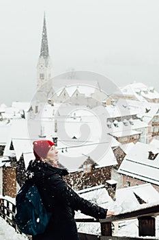 Woman in red hat enjoying the view over Hallstatt old town during snow storm, Austria